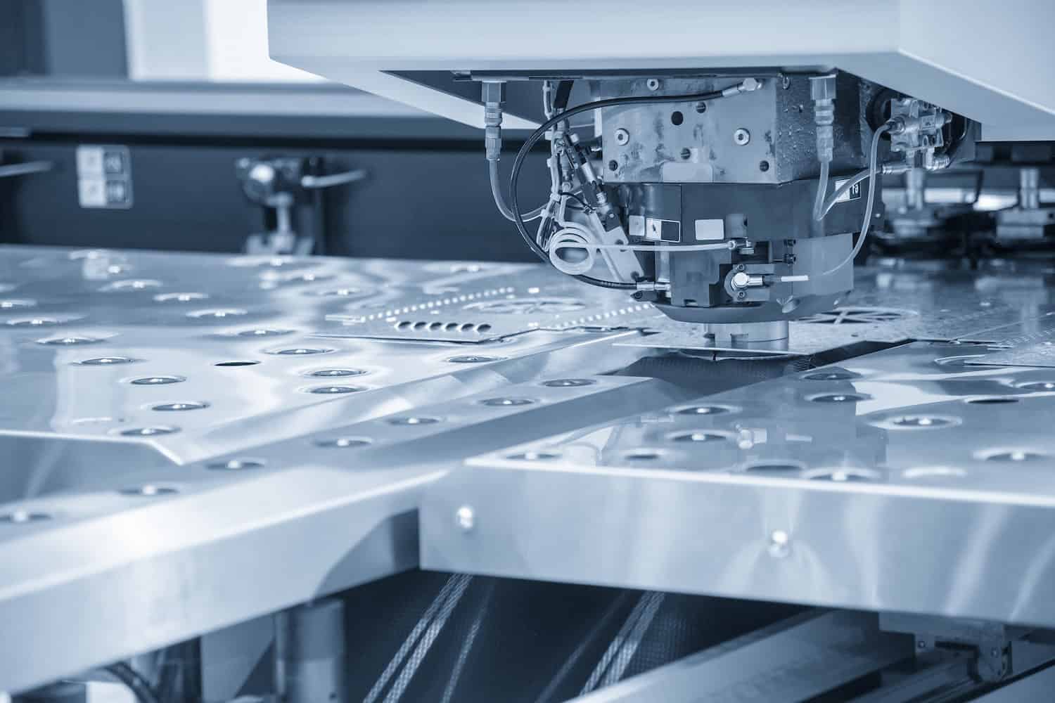 Turret punching machine cutting the metal plate. Metal forming machine. Close-up of an industrial CNC machine cutting or engraving patterns into a sheet of metal in a factory setting, showing precise automation technology in manufacturing.